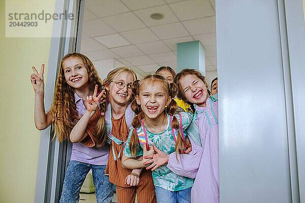 Happy school children smiling in classroom doorway