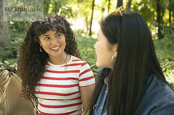 Smiling woman with curly hair talking with friend