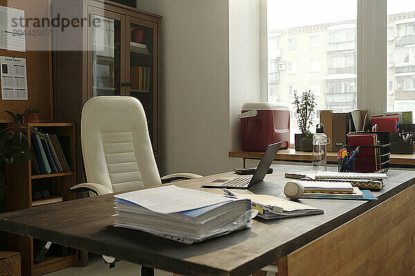 White chair near desk with office stationary and documents in university office