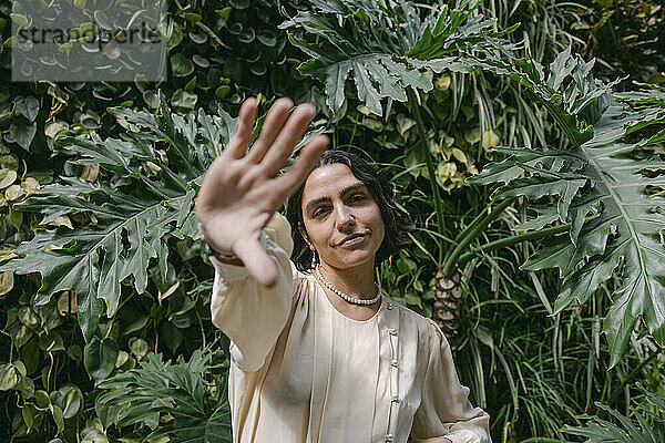 Smiling woman gesturing and standing in front of plants