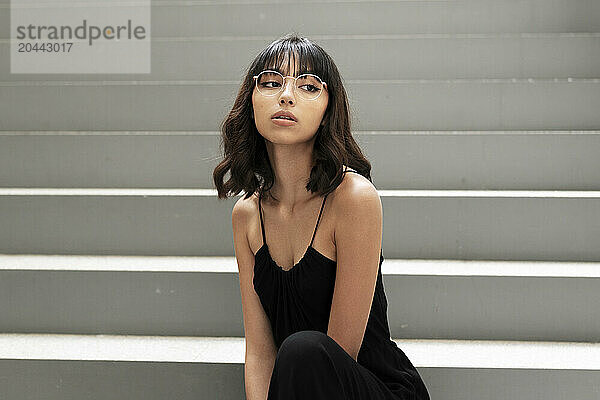 Young woman with bangs positing sitting on steps