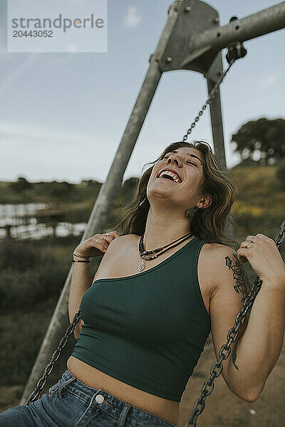 Young woman enjoys swinging in playground