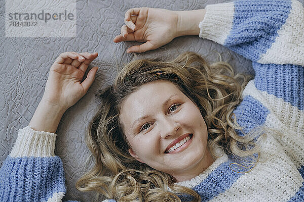 Happy woman lying on bed at home