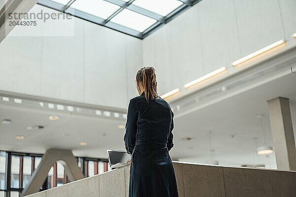 Businesswoman standing near desk and using laptop at airport