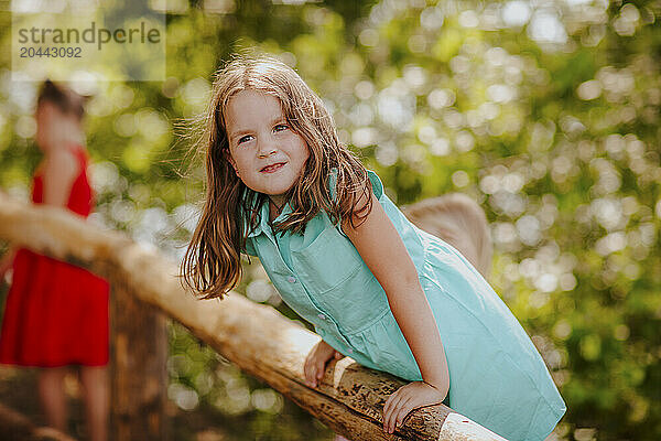 Girl climbing wooden fence at garden