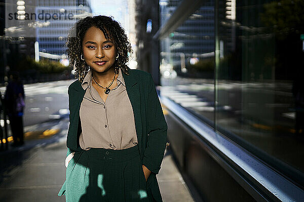 Smiling confident businesswoman standing with hands in pockets