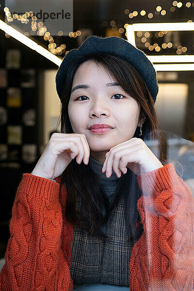 Beautiful young woman looking through window glass