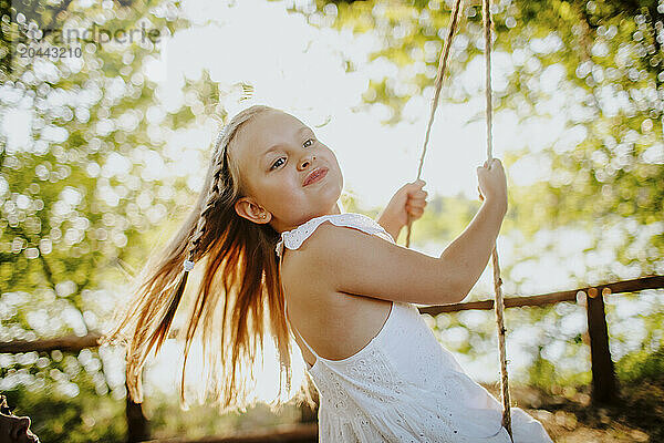 Blond girl enjoying swing at garden