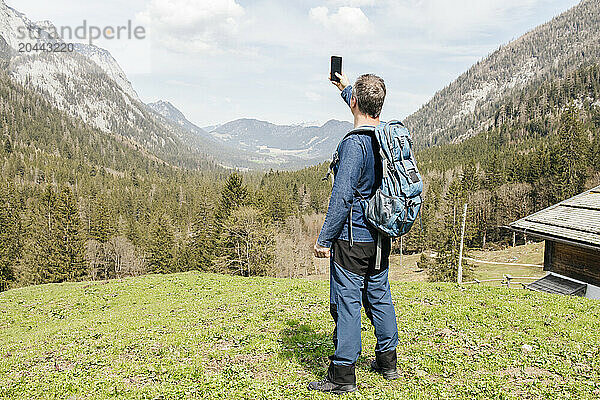 Man photographing mountains through mobile phone