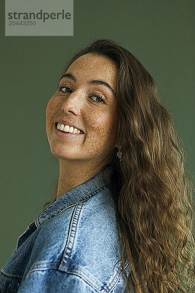 Smiling woman with freckles against green background