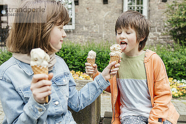 Sister sharing ice cream with brother near building