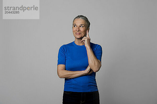 Contemplative senior woman in front of wall