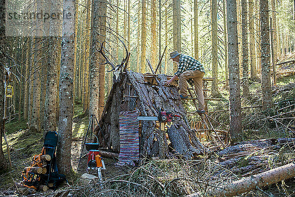 Senior man building shelter in forest