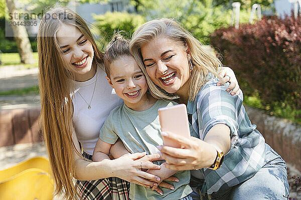 Happy mother taking selfie with son and daughter through smart phone