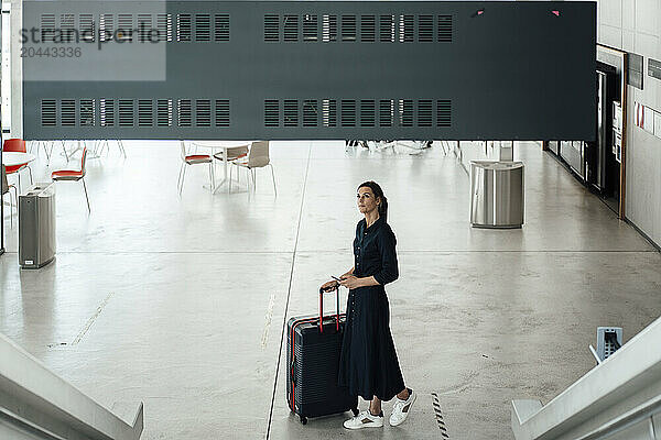 Businesswoman looking arrival departure board at airport