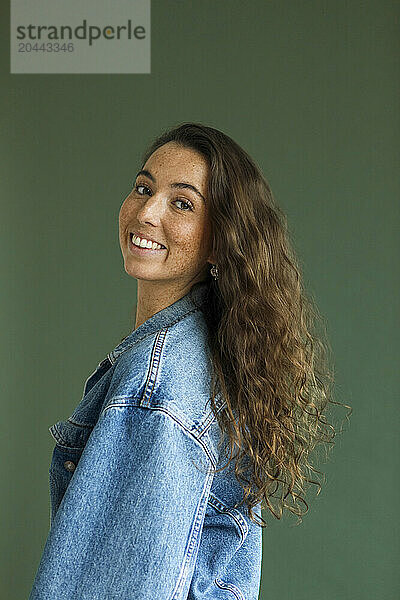 Smiling woman with brown hair against green background