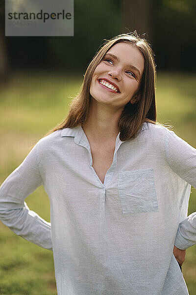 Thoughtful smiling woman standing at field