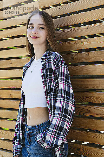 Smiling girl leaning on wooden wall