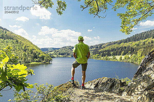 Man standing on rock near Obersee lake at north Rhine Westphalia  Eifel national park  Germany