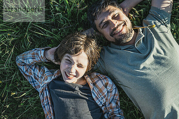 Happy father and son lying together on grass