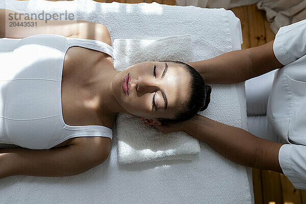 Hands of chiropractor treating teenage patient lying on massage table in clinic