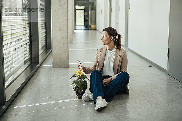 Businesswoman sitting next to flower pot at office