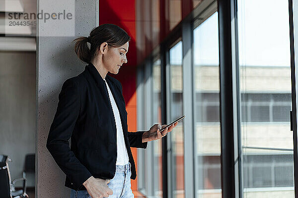 Businesswoman wearing black blazer using smart phone at office