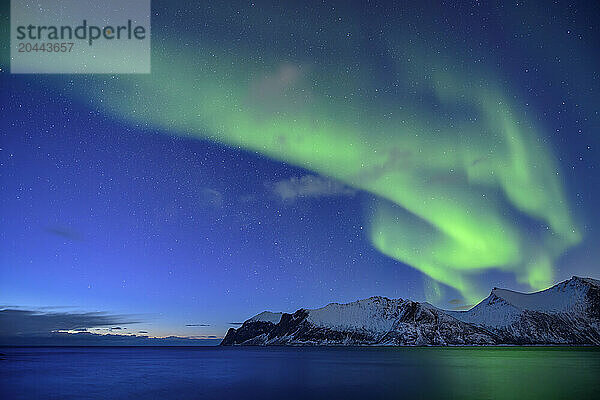 Northern lights with Norwegian sea and mountains at Senja island  Troms  Norway