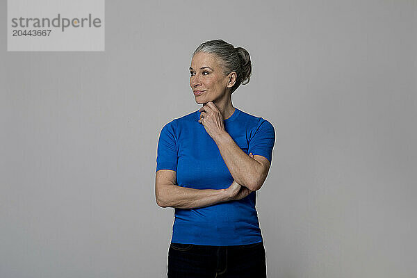 Senior woman wearing blue sweater in front of wall