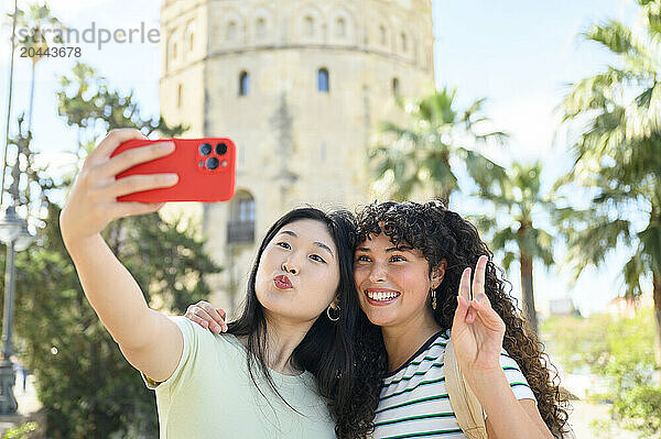 Cheerful friends taking selfie through smartphone in front of Torre del Oro