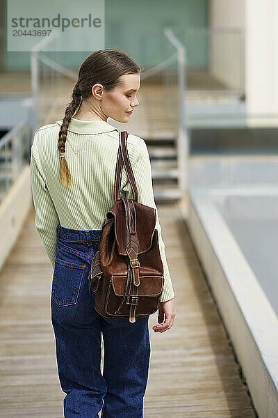 Woman holding backpack and standing at pier