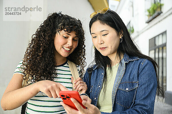 Young woman sharing smartphone with friend