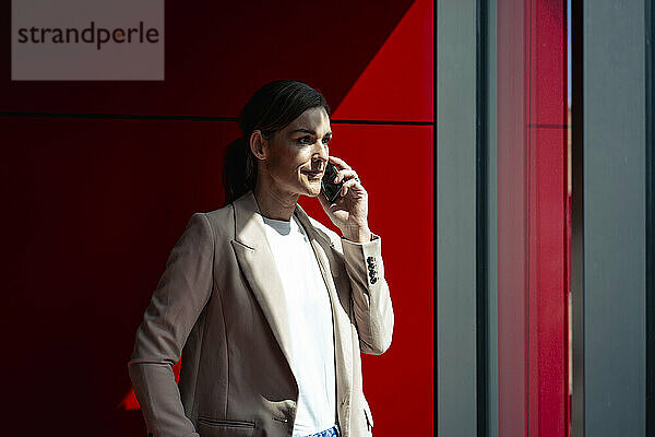 Businesswoman wearing blazer and talking on smart phone at office