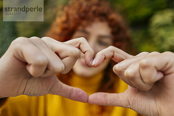 Young woman showing heart shape with hands