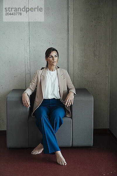 Business professional with crossed legs sitting on armchair at office