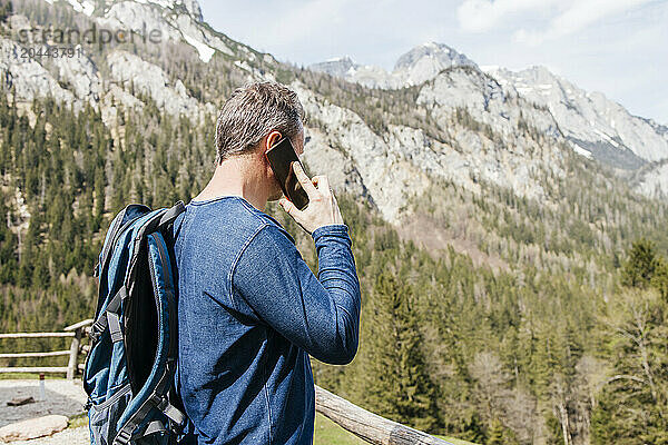 Man talking on smart phone in front of mountains