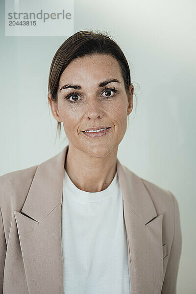 Smiling business person standing in front of wall at office