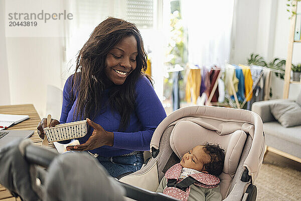 Happy working mother with daughter in baby carriage at home