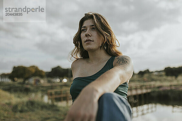 Contemplative woman in front of cloudy sky