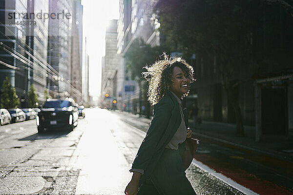 Happy businesswoman crossing street in city