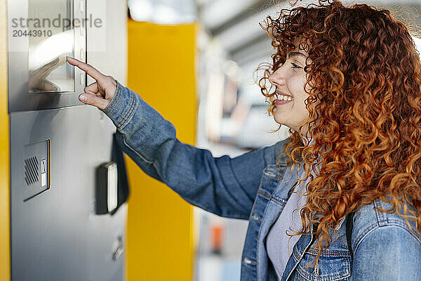 Smiling redhead young woman using kiosk