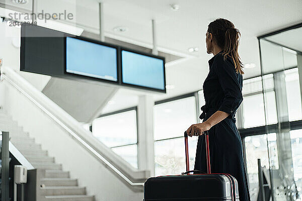 Businesswoman holding suitcase and waiting at airport