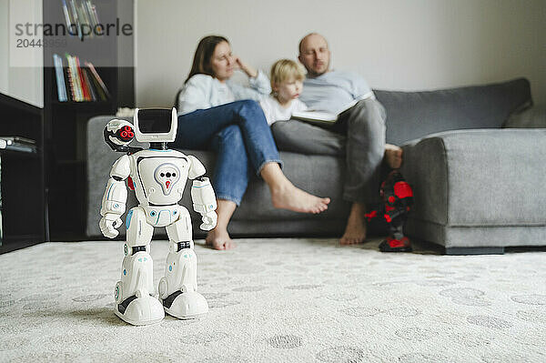 Toy robot on carpet in front of family at home