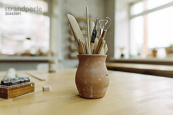 Ceramic tools and equipment kept in vase on table at workshop