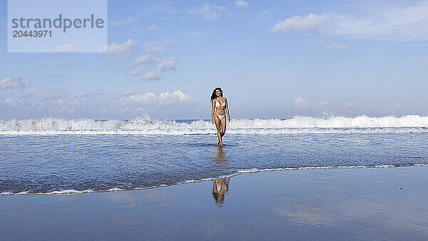 Woman wearing white bikini walking at beach