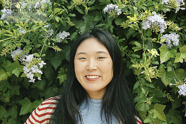 Smiling woman standing near flower at park