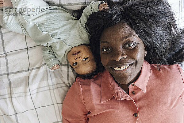 Happy woman and daughter lying down on bed at home