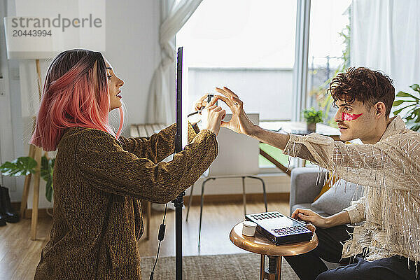 Influencers together adjusting mobile phone on ring light at home