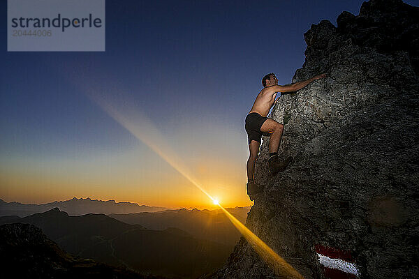 Hiker climbing Steinfeldspitze rock at sunrise in Altenmarkt  Zauchensee  Salzburg  Austria