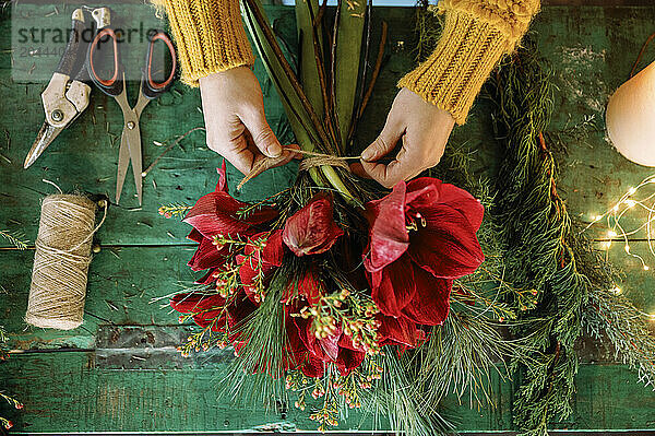 Florist tying thread on bouquet near table at store